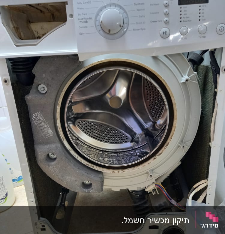 מכונת כביסה פתוחה עם תוף חשוף וחוטי חשמל